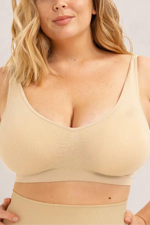 Mulher vestindo sutiã bege sem costura, modelo plus size, moda íntima confortável.