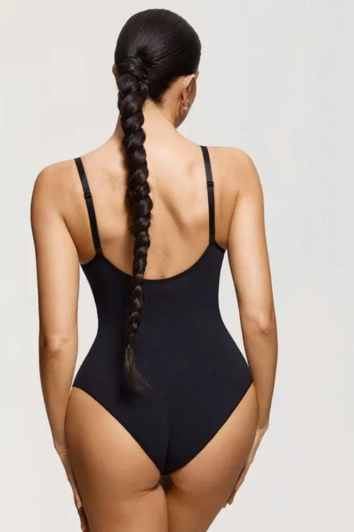 Mulher de costas usando body modelador preto com alças ajustáveis, fundo neutro.